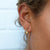 close up of woman wearing citrine crystal charm encased in gold hanging on a gold stud earring