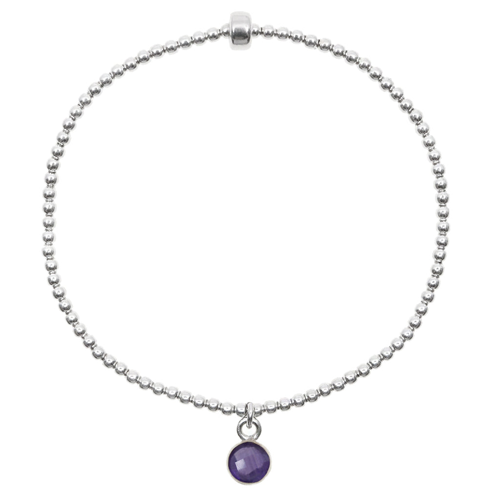 Dainty sterling silver beaded stretch bracelet featuring a natural amethyst charm encased in sterling silver.