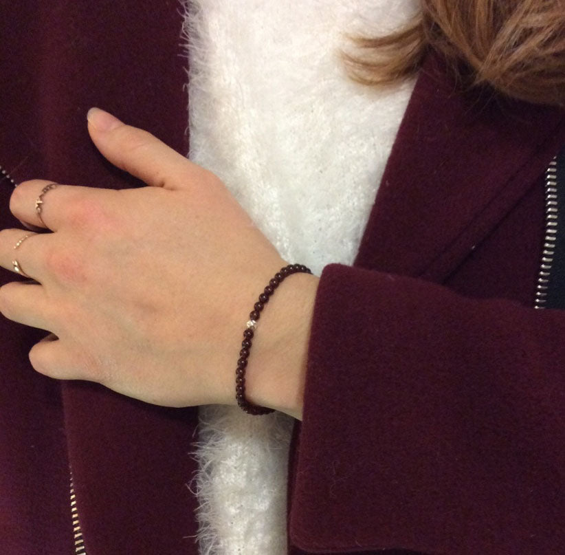 woman wearing garnet beaded stretch bracelet with sterling silver hammered accent